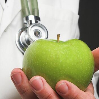 A doctor holding a green apple